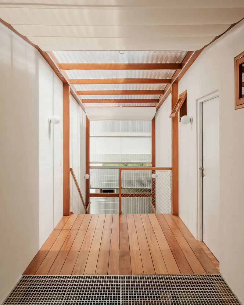 Upper hallway with timber flooring and exposed beams framing a wire mesh balustrade overlooking lower level