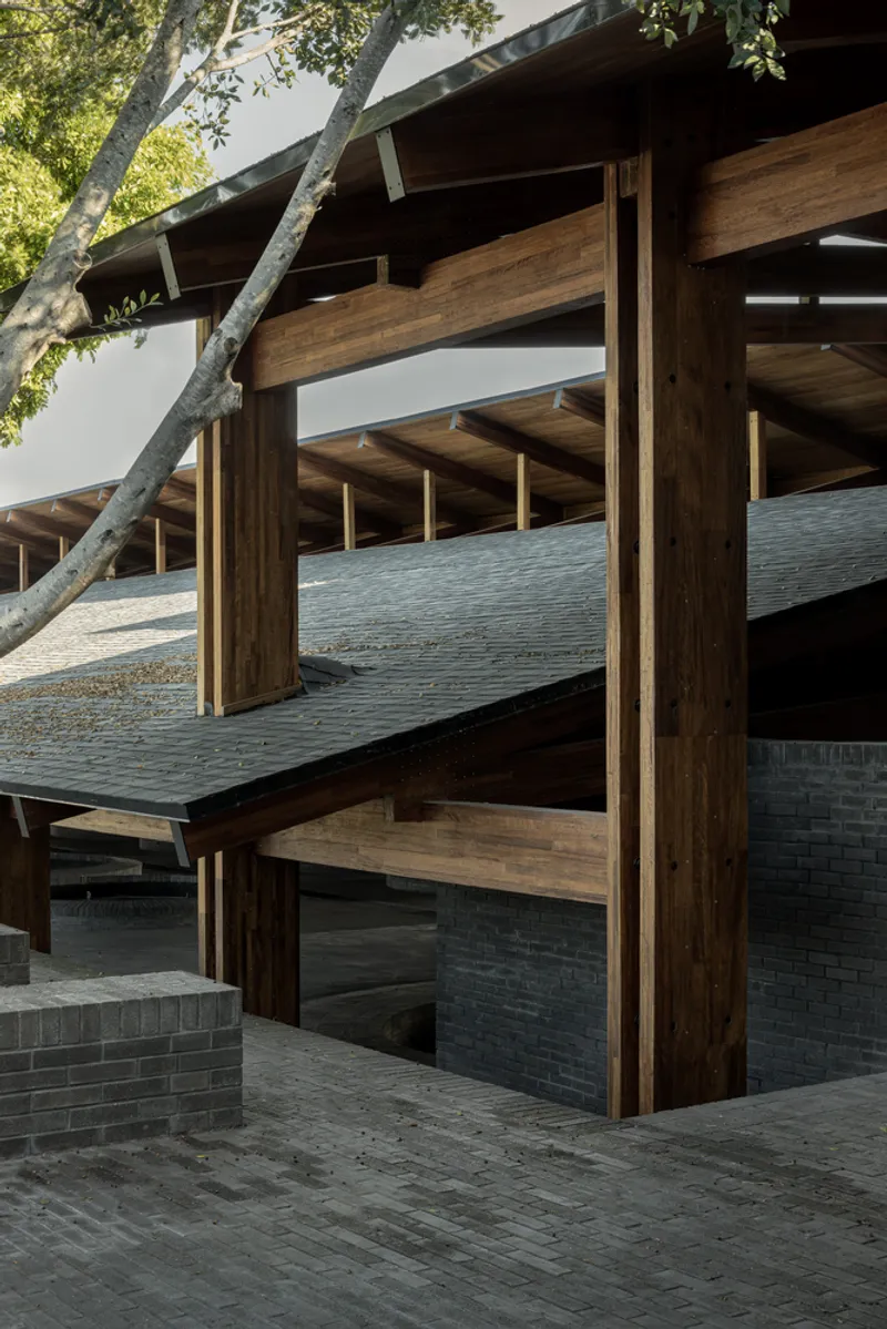 Covered terrace with timber columns and exposed beams above a dark brick base wall