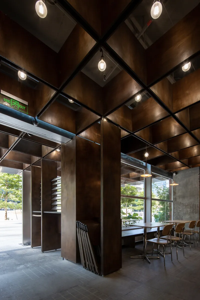 Angular view of the gridded timber ceiling with recessed lighting and steel structural columns below