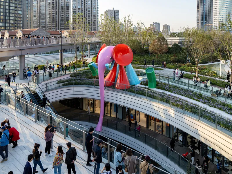 Rooftop terrace with colorful inflatable sculpture above a sunken courtyard with stepped landscaping