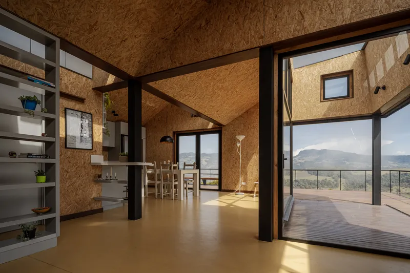 Living space with steel columns and large sliding doors opening onto timber deck with mountain views