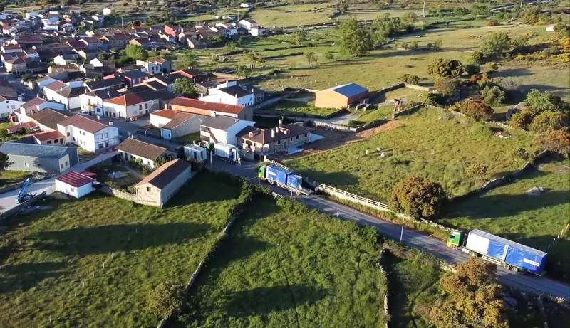 Aerial view of low-rise village with houses clustered along a road through green fields