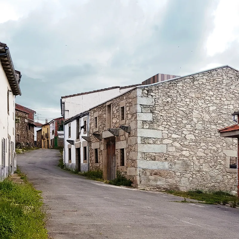 Stone and whitewashed facade along a narrow village street under overcast skies