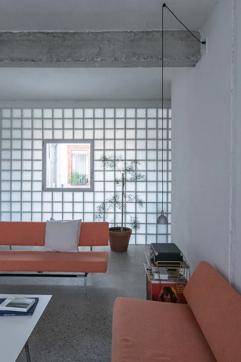 Seating area framed by glass block partition wall with exposed concrete beam overhead