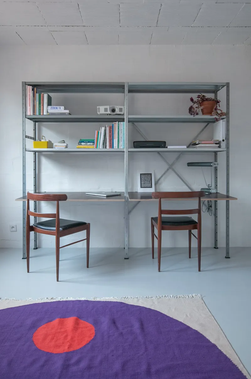 Workstation with grey steel shelving and purple geometric rug on polished concrete floor