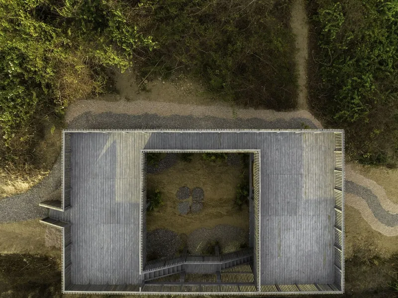 Aerial view of the slatted roof with central courtyard opening surrounded by gravel paths and vegetation