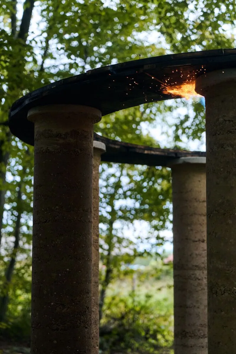 Sparks flying from torch contact point on the curved roof edge supported by earthen columns