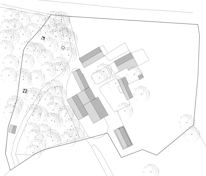 Site plan drawing showing clustered rectangular volumes among scattered vegetation and road access