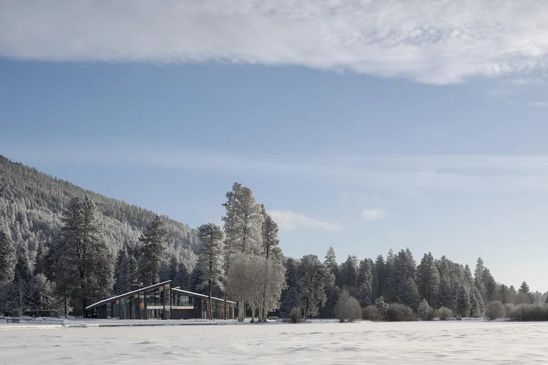 Distant view of the low horizontal structure across a snow-covered field with frost-edged conifers