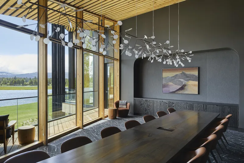 Dining room with timber slat ceiling and floor-to-ceiling glazing overlooking a lake and distant mountains