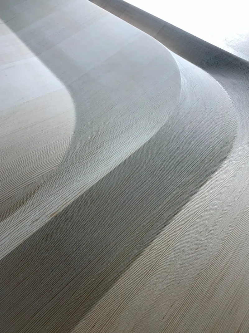 Close-up of fine linear wood floor grain with soft diagonal shadows crossing the surface