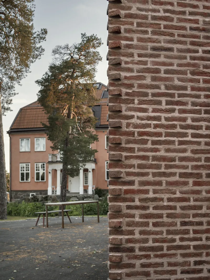 Detail of brick corner edge with neighboring residence and playground visible beyond in afternoon light