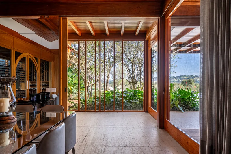 Hallway with floor-to-ceiling window wall opening to planted courtyard with clustered tree trunks