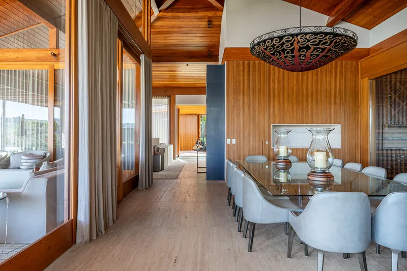 Dining area with timber paneled wall and clerestory windows framing views to adjacent living spaces