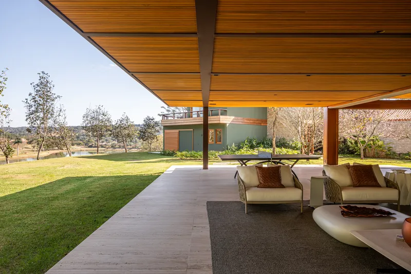 Sheltered outdoor living area with deep roof overhang framing views across the grass field