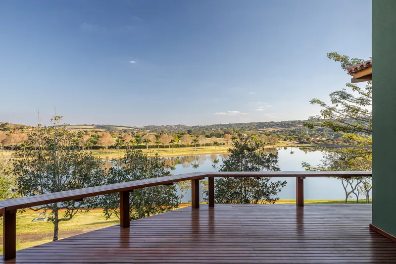 Timber deck with metal railing overlooking a lake and rolling hillside in afternoon light