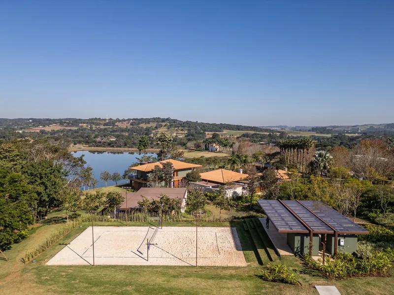 Aerial view of compound showing sand volleyball court, rooftops and lake beyond at midday