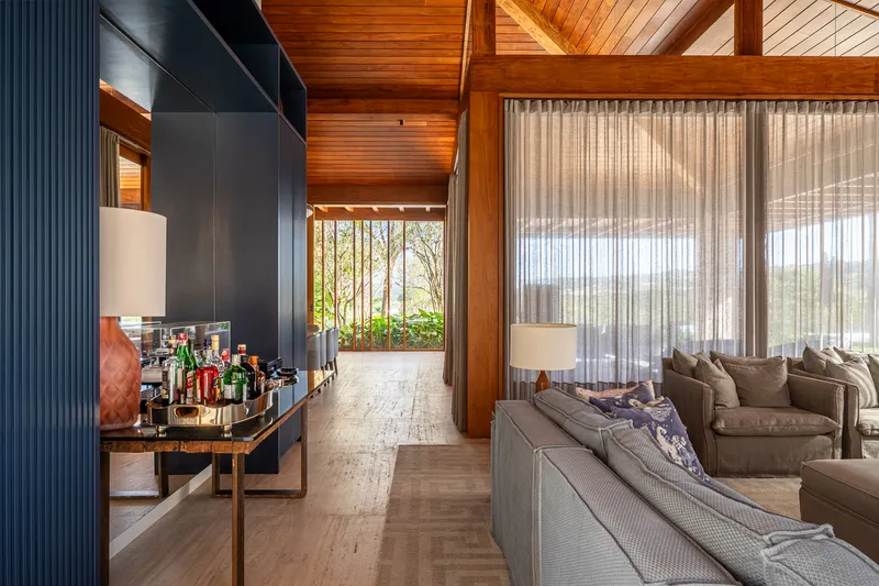 Living room with timber ceiling, dark fluted wall panels and sheer curtains filtering daylight