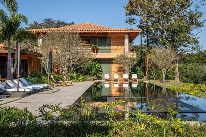 Rectangular infinity pool with stone deck reflecting the terracotta tile roof and surrounding palm trees