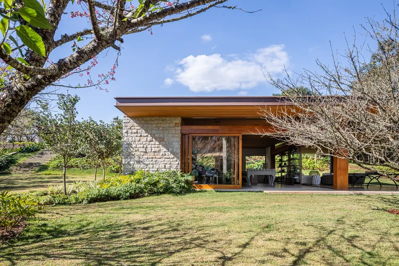 Garden facade showing light stone masonry wall and timber framed opening beneath a broad roof overhang
