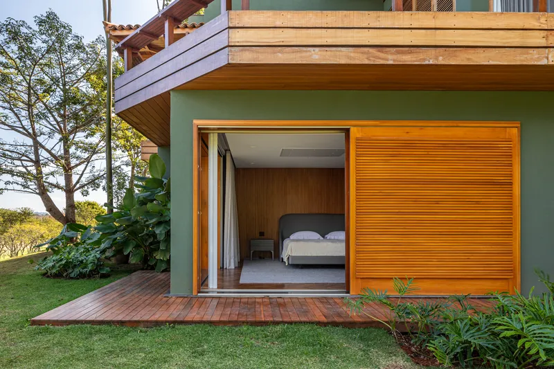 Bedroom terrace opening with timber decking, orange slatted screen and planted edges under afternoon sun