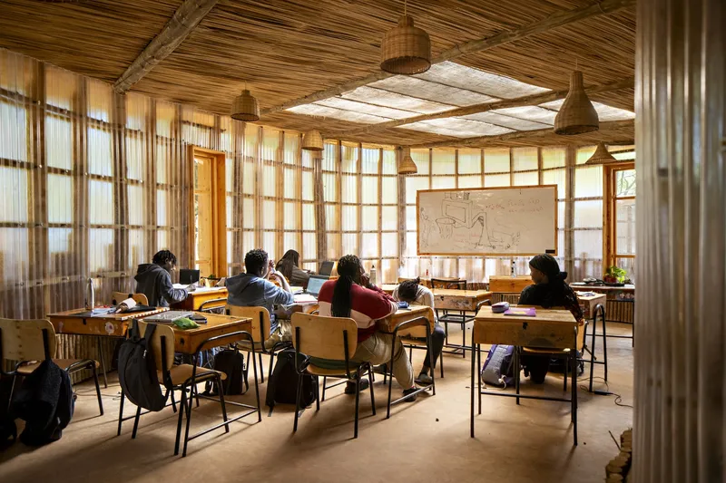 Classroom interior with translucent corrugated wall panels, timber ceiling structure, and students seated at wooden desks
