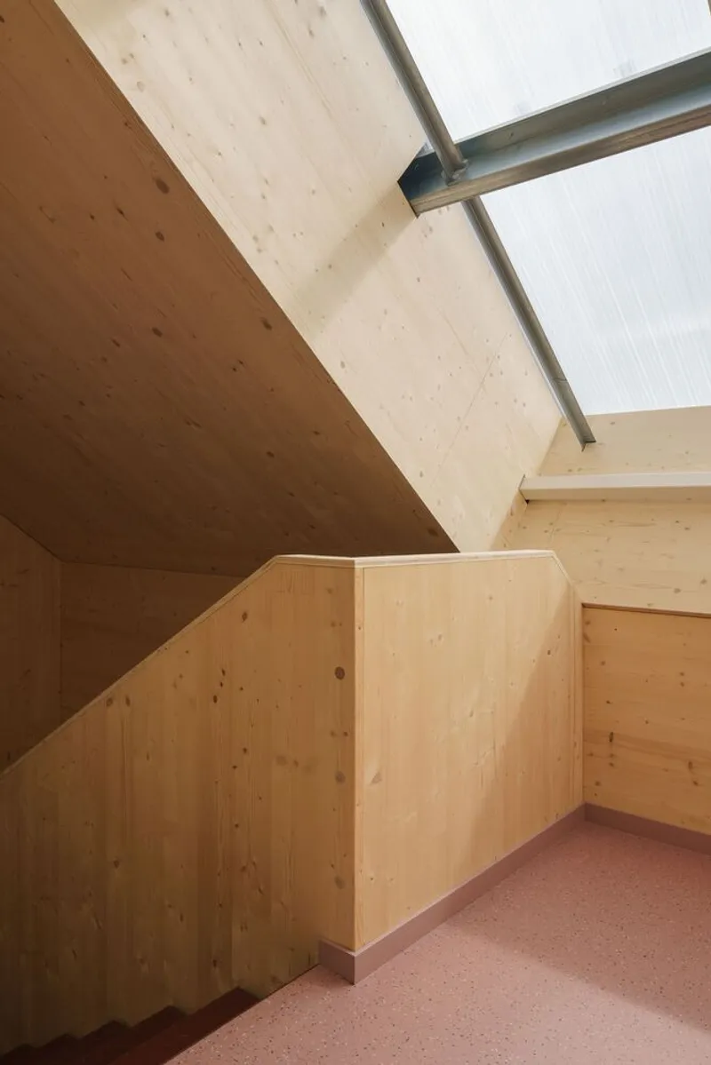Upper stair landing with angled plywood ceiling and translucent polycarbonate wall panels