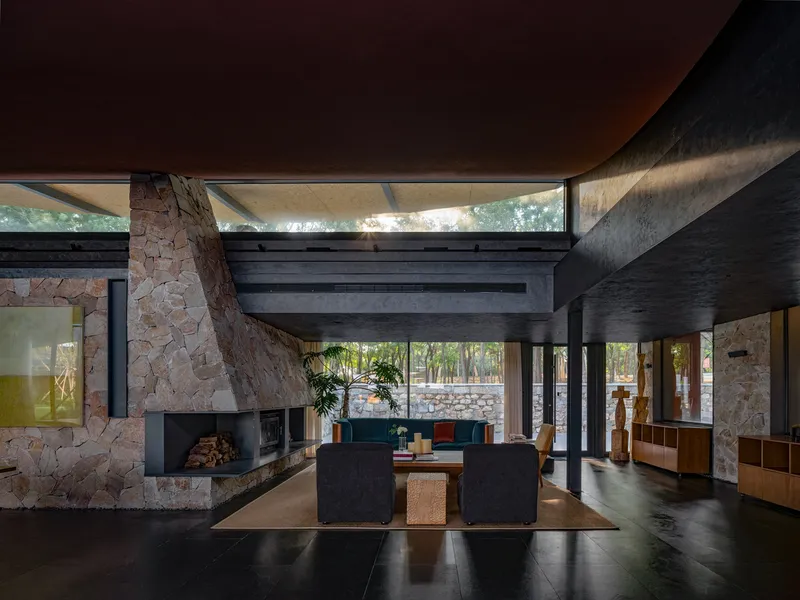 Living room with angled stone fireplace wall and clerestory glazing bringing in late afternoon light