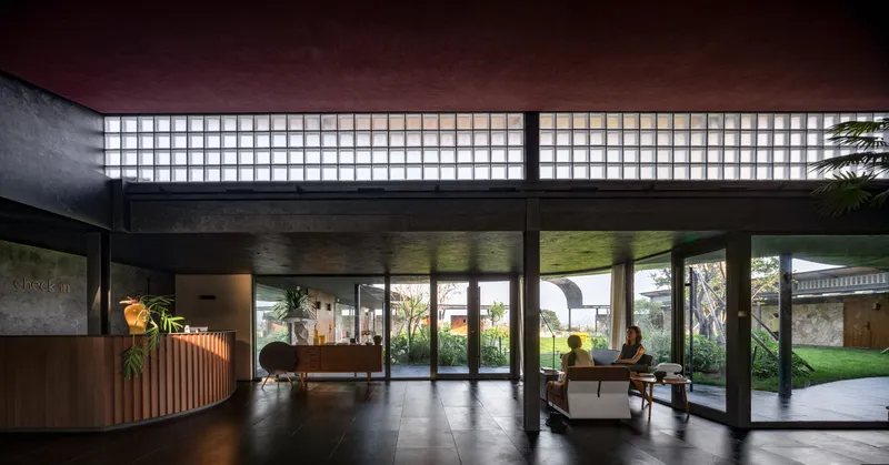 Reception lobby with gridded glass block clerestory windows and full-height glazing overlooking a courtyard garden