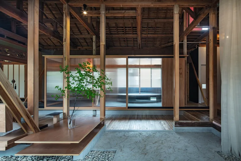 Raised timber floor platform with translucent sliding screens and small tree in glass vase
