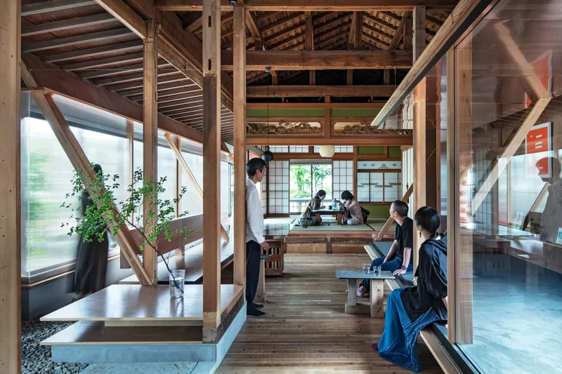Interior view of timber post and beam structure with visitors seated on benches under exposed rafters