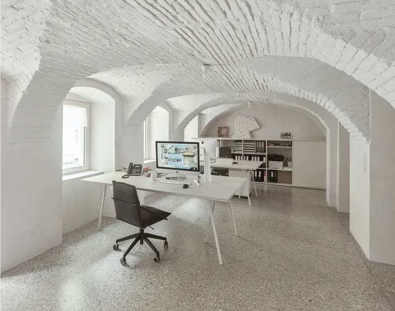 White vaulted brick ceiling with radiating ribs above an office workspace with terrazzo flooring