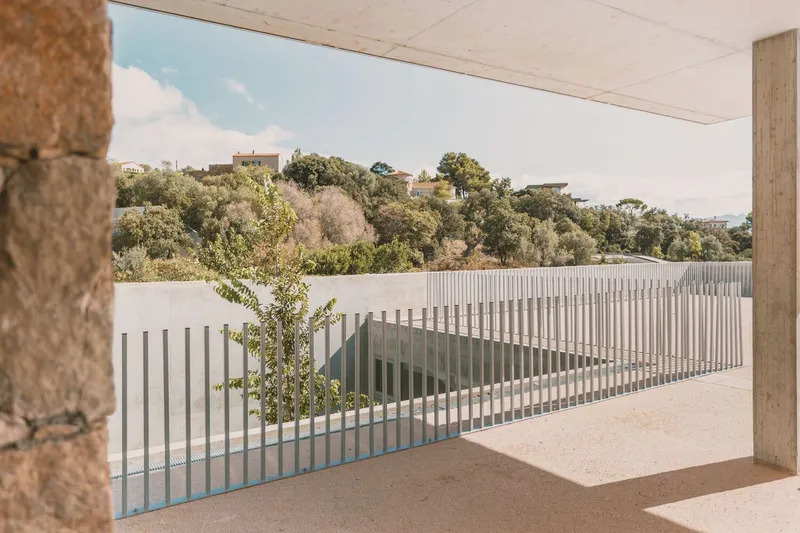 Covered terrace view of vertical metal screen facade with hillside village in the distance