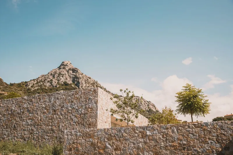 Layered stone walls stepping down the hillside with scattered trees emerging above them