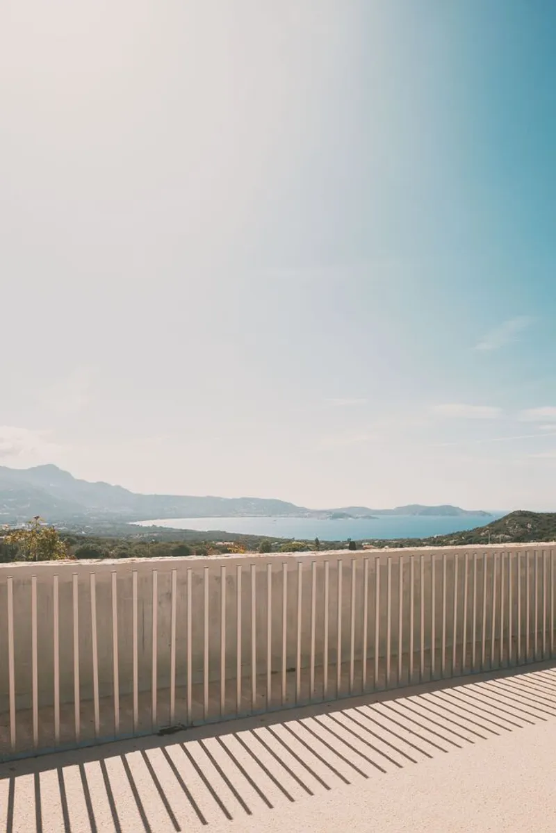 Timber slatted screen casting parallel shadows on a terrace overlooking distant mountains and water