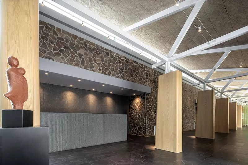 Entry hall with freestanding oak columns and terracotta sculpture beside the stone feature wall