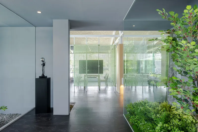 Corridor view with planted courtyard and green glass block screen framed by white columns
