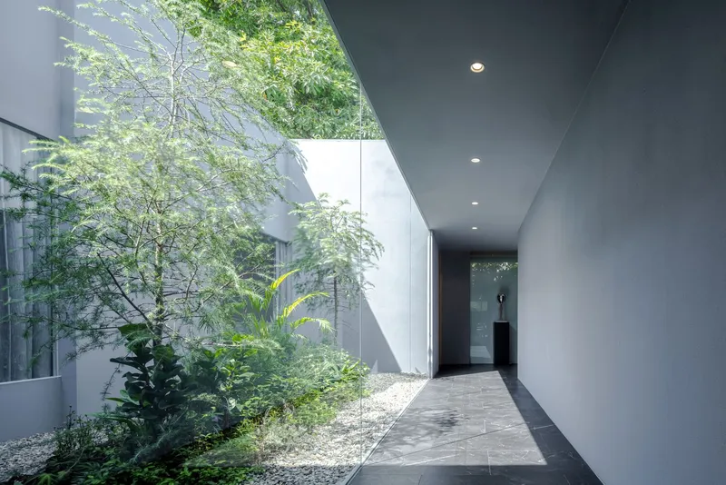 Covered walkway with planted courtyard garden along one side beneath a dark grey ceiling