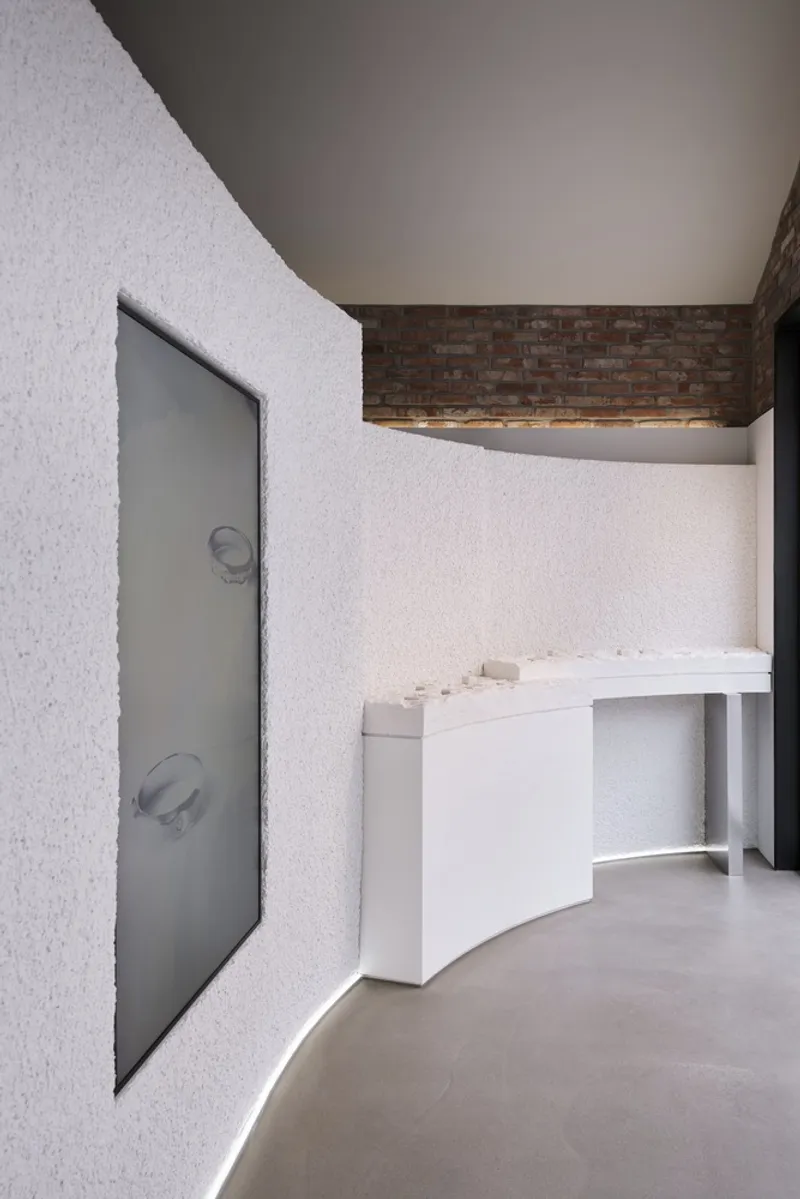 Textured white wall with recessed frosted glass panel and floating white display counter