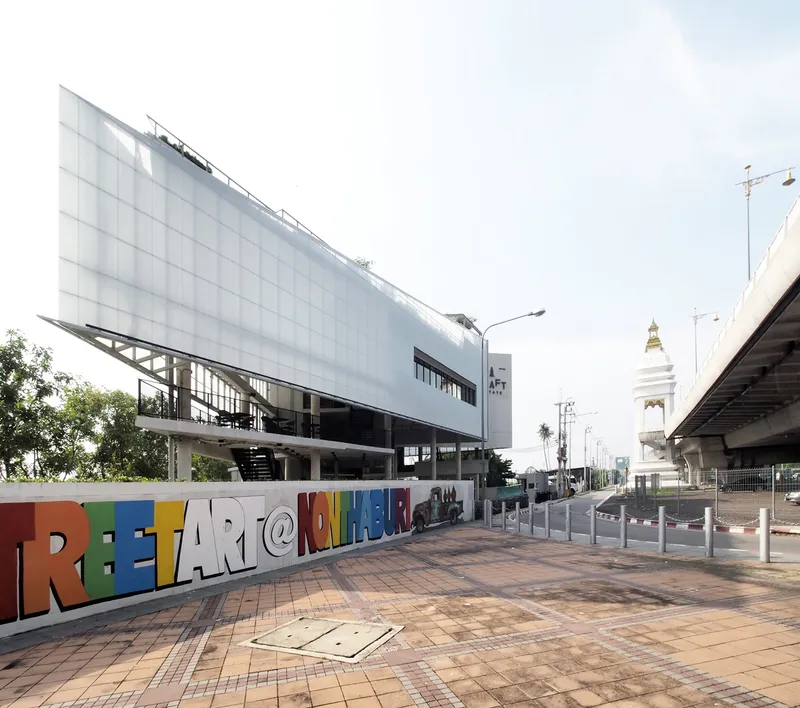 Street view showing the translucent screen facade above concrete columns with highway overpass in background