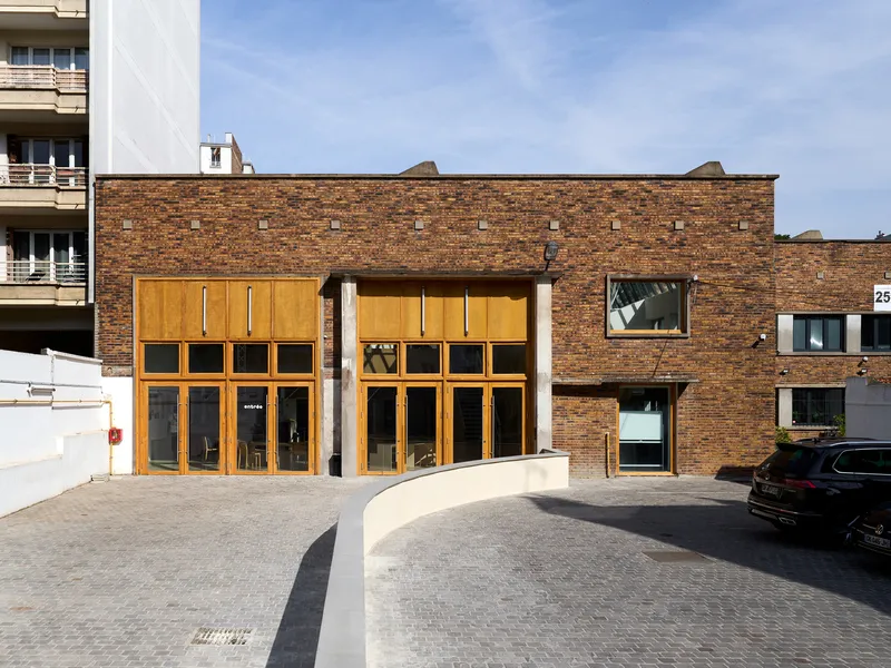 Street facade with timber-framed glazing inserted into an existing brown brick industrial wall