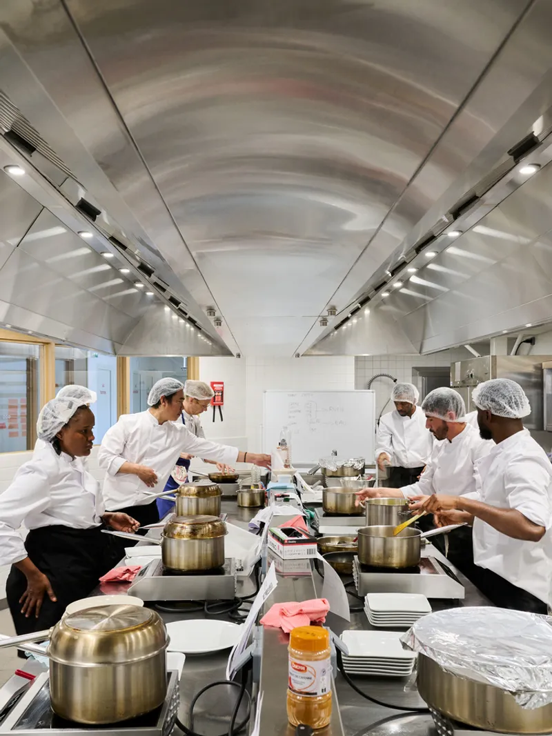 Vaulted metal ceiling with recessed lighting above the central kitchen island during a training session