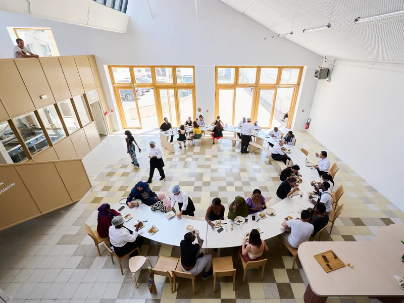 Top-down view of the dining space with round tables on checkered vinyl flooring beneath sloped windows