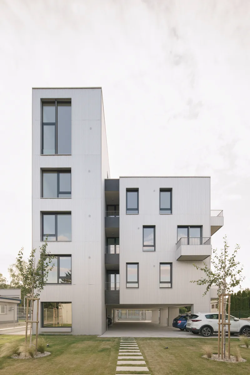 Front elevation showing stepped volumes with open ground floor carport under overcast sky