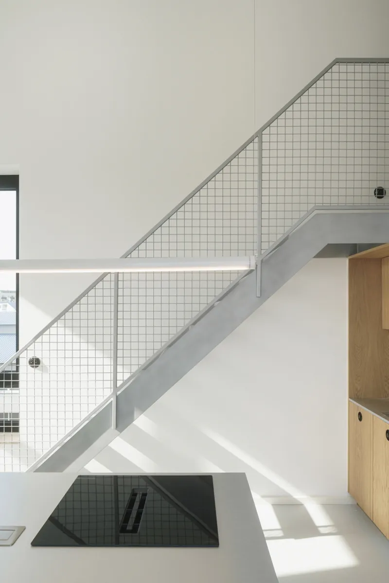 Metal staircase with wire grid infill panels and sunlight casting shadows on white walls