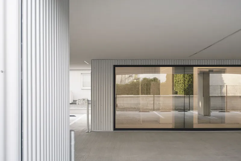 Ground floor passage with fluted column wrapping and full-height glazed opening to exterior