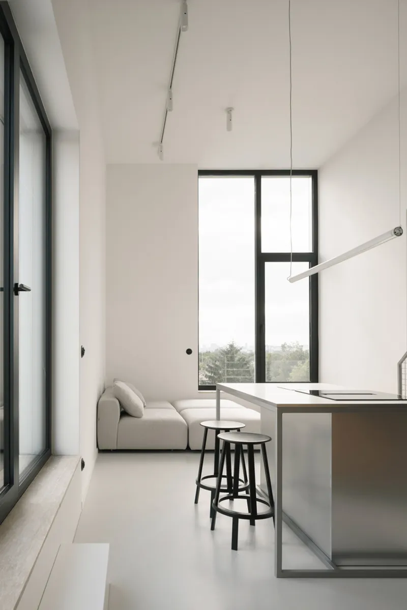 Living space with tall window overlooking distant trees and a suspended pendant light