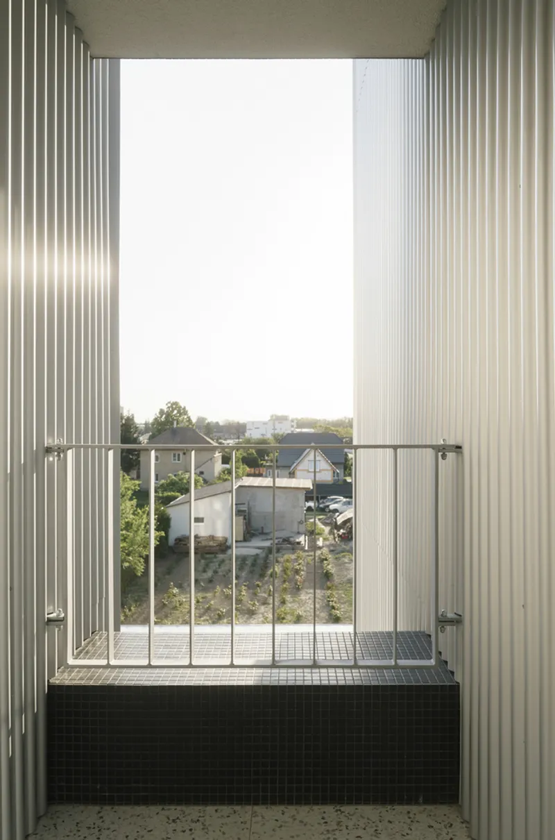 Balcony with black mosaic tile parapet and steel railing framing view of neighboring houses