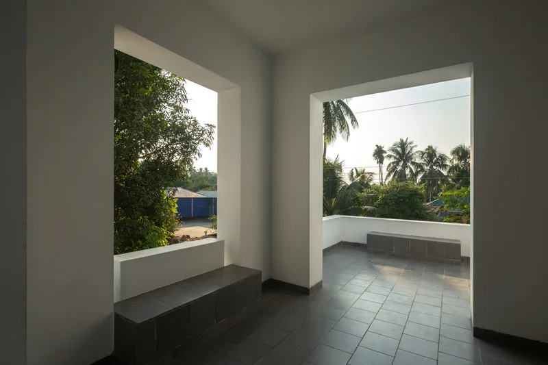 Interior corridor with two framed openings overlooking palm trees and neighboring rooftops in daylight