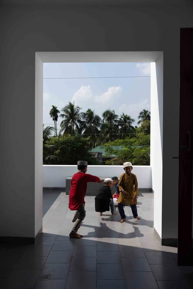 Three children playing on an outdoor terrace framed by a wide doorway with palm trees beyond